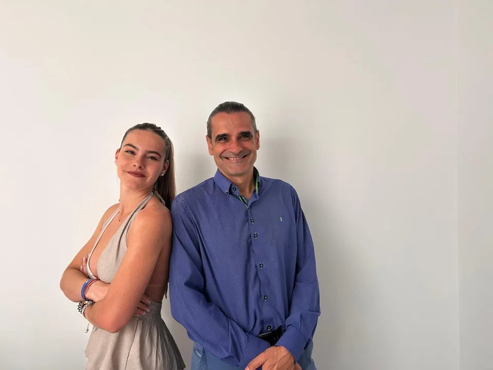 Antonio y Noelia, el equipo de Inmobiliaria Arenas, sonriendo ante una pared blanca